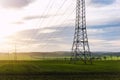 Scenic view of electricity pylons stretching across green fields warm sunset sky background. Electric power supply high Royalty Free Stock Photo