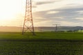 Scenic view of electricity pylons stretching across green fields warm sunset sky background. Electric power supply high Royalty Free Stock Photo