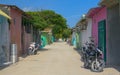 Scenic view of an empty dirt road running past colorful local houses in Maldives Royalty Free Stock Photo