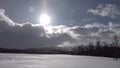 Scenic view at fast moving clouds with drifting snow flies over white field with mountain at background in Swedish Lappland.