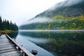a scenic view of a fishing pier on a foggy mountain lake