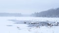 Scenic view a frozen lake with a water hole in the shore of the forest Royalty Free Stock Photo