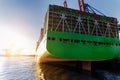 Scenic view giant cargo container ship loading Hamburg city port harbour against seaport cranes warm evening sunset Royalty Free Stock Photo