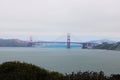 Scenic view of Golden Gate Bridge from the shore partially covered in fog in San Francisco