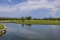 Scenic view of golf course landscape featuring lake with young couple enjoying game of golf on island of Aruba