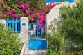 Scenic view on the Greek white stone house with beautiful plants and growing in garden bougainvillea. Santorini island.