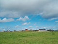 Scenic view of a green field against houses and a cloudy blue sky in Sianozety, Poland Royalty Free Stock Photo