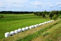 Scenic view of hay bales in a green field in the countryside under a cloudy blue sky Royalty Free Stock Photo