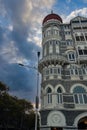 Scenic view of the iconic Taj Mahal Palace in Mumbai, India, against a dramatic, cloudy sunset sky