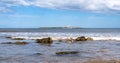 Scenic view of an island in a sea against a rocky beach under a  cloudy blue sky Royalty Free Stock Photo