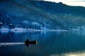 Scenic view of Kopaonik mountain and a man on a fishing boat in Celije Lake during winter in Serbia Royalty Free Stock Photo