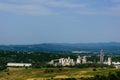 Scenic view of landscape with huge cement factory surrounded by green vegetation