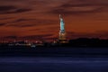 Scenic view of Liberty statue on the coast under the orange and cloudy sunset sky Royalty Free Stock Photo