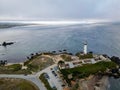 Scenic view of a lighthouse perched on a grassy hilltop overlooking the vast expanse of the ocean