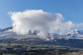 A scenic view of majestic snowy mountain with frosty pine forest under a majestic blue sky and some white clouds Royalty Free Stock Photo