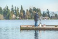 Scenic view of a man fishing on a pier in a big lake in the park. Royalty Free Stock Photo