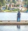 Scenic view of a man fishing on a pier in a big lake in the park. Royalty Free Stock Photo