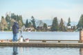 Scenic view of a man fishing on a pier in a big lake in the park. Royalty Free Stock Photo