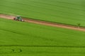 Scenic View Of Modern Farming Tractor Which Plowing Green Field. Agriculture Tractor Cultivating Wheat Field And Creating Green Ab Royalty Free Stock Photo