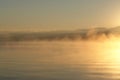 A scenic view - morning fog over the calm water of Baikal Lake. Golden sunrise at Chivyrkuisky Bay Royalty Free Stock Photo