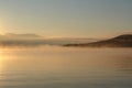 A scenic landscape - morning fog over the calm water of Chivyrkuisky Bay, Buryatia Royalty Free Stock Photo