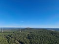 Scenic view of mountain forest with tall wind turbines on it under the clear sky