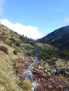Scenic view of a narrow stream surrounded by rocks with mountains in the background Royalty Free Stock Photo