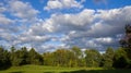 Scenic view of the park with green trees and grass field in city and a cloudy blue sky background Royalty Free Stock Photo