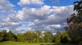 Scenic view of the park with green trees and grass field in city and a cloudy blue sky background Royalty Free Stock Photo