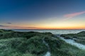 Scenic view of a path through a sandy beach covered with greenery at sunset Royalty Free Stock Photo