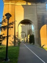 Scenic view of a pathway under a series of large stone arches with sunlight casting shadows.