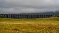 Scenic view of a railway bridge on a cloudy day, with grassy landscape in the foreground Royalty Free Stock Photo