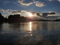 Scenic view of a reflective lake with a lonely boat on the middle under the cloudy sunset sky Royalty Free Stock Photo