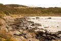 Scenic view of a rocky shore surrounded by hills covered in deserty greenery Royalty Free Stock Photo