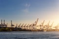 Scenic view row big cargo container ship loading Hamburg city port harbour seaport cranes at warm morning sunrise light Royalty Free Stock Photo