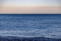 Scenic view of a sailboat gliding across a tranquil sea at sunset