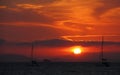 several sail boats on a body of water as the sun rises