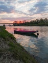 Scenic view of the Sava River in Bosanski Brod with a boat moored in front and the silhouette of a forest and a bridge in the