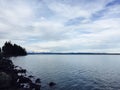 Scenic view of a serene lake shore against a backdrop of a bright blue sky and snow-capped mountains