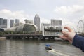 Scenic view of Singapore Hand with a smartphone, on the screen of which the urban landscape