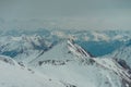 Scenic view of snow-covered mountains beneath a blanket of large, fluffy clouds