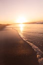 Scenic view of sunlight reflecting on sea and waves splashing at shore against clear sky at sunset Royalty Free Stock Photo