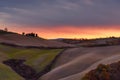 Scenic view of the Tuscan landscape at sunset with a farmhouse at the top of a hill Royalty Free Stock Photo