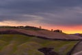 Scenic view of the Tuscan landscape at sunset with a farmhouse at the top of a hill Royalty Free Stock Photo