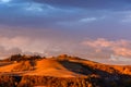 Scenic view of the Tuscan landscape at sunset with a farmhouse at the top of a hill Royalty Free Stock Photo