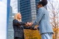 Scenic view of two multi-ethnic businesswomen greeting each other outside of the office