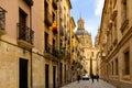 Narrow cobbled street in Salamanca against backdrop of baroque dome of La Clerecia