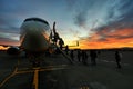 Scenic view of unrecognizable passengers silhouette boarding on airplane at sunset