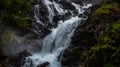 Scenic view of a waterfall flowing over the mossy rocky mountains