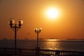 View of waterfront with lanterns backlit by setting sun and with ships in the roadstead Royalty Free Stock Photo